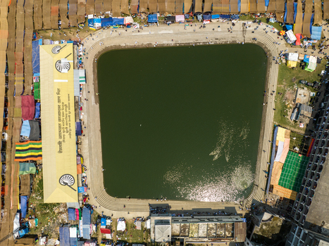 Aerial view of a large pond reflecting the sky surrounded by vibrant tents and structures creating a lively scene Charmonai Barisal Division Bangladesh. Aerial view of a large pond reflecting the sky surrounded by vibrant tents and structures creating a lively scene Charmonai Barisal Division Bangladesh.