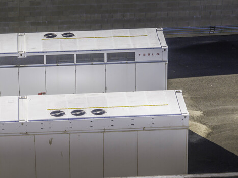 Aerial view of Tesla Megapack battery storage units with cooling fans and industrial white containers on an asphalt lot Los Angeles County California United States. Aerial view of Tesla Megapack battery storage units with cooling fans and industrial white containers on an asphalt lot Los Angeles County California United States.