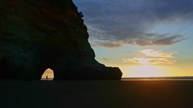 View of a natural archway and person at sunset New Zealand. View of a natural archway and person at sunset New Zealand.
