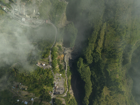 Aerial view of Tambang Pasir Merapi Kali Gendol Sand Mine with deep ravines lush vegetation and buildings under a light mist in Kecamatan Cangkringan Daerah Istimewa Yogya Indonesia. Aerial view of Tambang Pasir Merapi Kali Gendol Sand Mine with deep ravines lush vegetation and buildings under a light mist in Kecamatan Cangkringan Daerah Istimewa Yogya Indonesia.