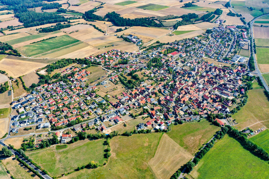 Aerial view of the town of Lonnerstadt featuring red roofed houses and a church spire surrounded by green meadows and agricultural fields Lonnerstadt Bavaria Germany. Aerial view of the town of Lonnerstadt featuring red roofed houses and a church spire surrounded by green meadows and agricultural fields Lonnerstadt Bavaria Germany.