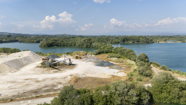 Aerial view of Extraccion de aridos Lima S.L. gravel site with sand piles machinery and lake waters in Vilarino das Poldras Ourense Spain. Aerial view of Extraccion de aridos Lima S.L. gravel site with sand piles machinery and lake waters in Vilarino das Poldras Ourense Spain.