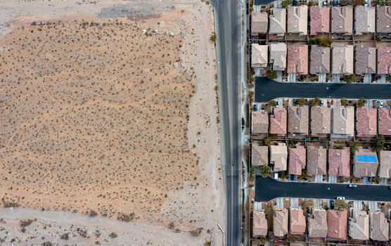 Aerial view of the boundary between arid desert terrain and a suburban residential neighborhood with houses and paved streets in Las Vegas Nevada United States. Aerial view of the boundary between arid desert terrain and a suburban residential neighborhood with houses and paved streets in Las Vegas Nevada United States.