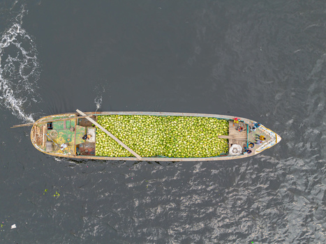 Dhaka Bangladesh 04 April 2026 Aerial view of a boat brimming with light green gourds sailing on the dark waters of the river creating a striking contrast. Dhaka Bangladesh 04 April 2026 Aerial view of a boat brimming with light green gourds sailing on the dark waters of the river creating a striking contrast.