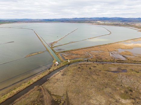 Aerial view of Lake Atanasovsko featuring salt pans narrow dikes and a small building by a canal under a cloudy sky Burgas Burgas Bulgaria. Aerial view of Lake Atanasovsko featuring salt pans narrow dikes and a small building by a canal under a cloudy sky Burgas Burgas Bulgaria.