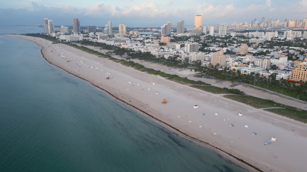 Aerial view of the sandy coastline turquoise ocean waters iconic lifeguard towers and the city skyline of Miami Beach Florida United States. Aerial view of the sandy coastline turquoise ocean waters iconic lifeguard towers and the city skyline of Miami Beach Florida United States.