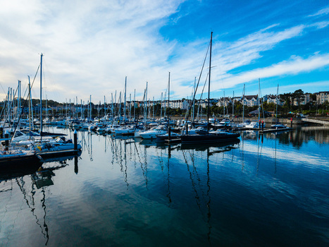 Aerial view of Bangor Harbour and Town with numerous sailboats and yachts moored in the calm water reflecting the blue sky and surrounding buildings in Bangor Northern Ireland United Kingdom.