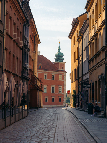 View of the historic Warsaw Old Town with cobblestone streets colorful facades and a person sitting on steps in Warsaw Masovian Voivodeship Poland. View of the historic Warsaw Old Town with cobblestone streets colorful facades and a person sitting on steps in Warsaw Masovian Voivodeship Poland.