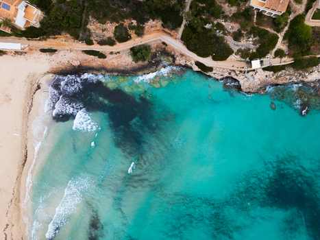 Aerial view of the turquoise waters and rocky coastline with people walking along the coastal path Cala Mendia Illes Balears Spain. Aerial view of the turquoise waters and rocky coastline with people walking along the coastal path Cala Mendia Illes Balears Spain.