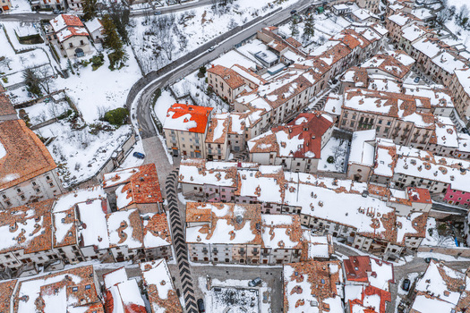 Aerial view of the historic town of Pescocostanzo with snow covered red tiled rooftops and narrow streets in Pescocostanzo Abruzzo Italy.