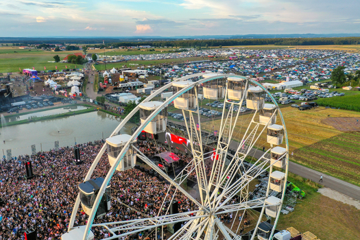 Herzogenaurach Germany 24 July 2025 Aerial view of Open Beatz Festival featuring a large white ferris wheel a dense crowd of people and various stages across the festival grounds.
