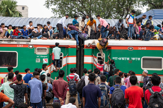 Dhaka Bangladesh 15 June 2018 View of Airport Railway Station with a crowded train where passengers sit on the roof and hang from the doors during a busy travel period. Dhaka Bangladesh 15 June 2018 View of Airport Railway Station with a crowded train where passengers sit on the roof and hang from the doors during a busy travel period.