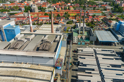 Aerial view of an industrial factory complex with tall chimneys and warehouse rooftops overlooking a residential town area in Kyjov South Moravian Region Czechia.