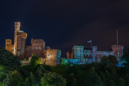 View of the illuminated Inverness Castle at night with its historic stone towers and surrounding trees in Inverness Scotland United Kingdom. View of the illuminated Inverness Castle at night with its historic stone towers and surrounding trees in Inverness Scotland United Kingdom.