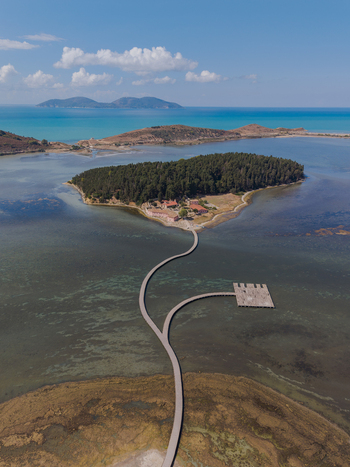 Aerial view of Zvernec Monastery on Zvernec Island connected by a long wooden footbridge across the shallow waters of Narta Lagoon in Vlore Vlore County Albania. Aerial view of Zvernec Monastery on Zvernec Island connected by a long wooden footbridge across the shallow waters of Narta Lagoon in Vlore Vlore County Albania.