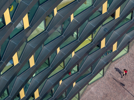 Aerial view of a modern building facade featuring geometric dark metal panels and glass windows with a person walking on the paved ground below in Belgrade City of Belgrade Serbia. Aerial view of a modern building facade featuring geometric dark metal panels and glass windows with a person walking on the paved ground below in Belgrade City of Belgrade Serbia.