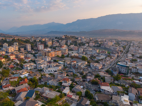 Aerial view of the historic stone houses and red tiled roofs of the old town nestled against a mountainous landscape in Gjirokaster Gjirokaster County Albania. Aerial view of the historic stone houses and red tiled roofs of the old town nestled against a mountainous landscape in Gjirokaster Gjirokaster County Albania.