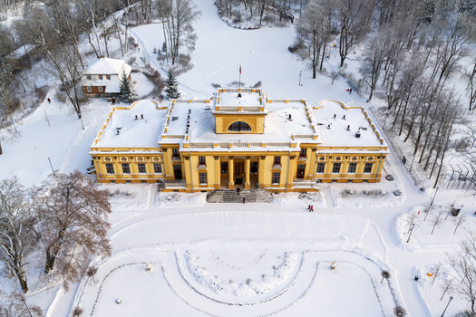 Aerial view of the yellow Traku Voke Manor house surrounded by snow covered trees and a winter park in Vilnius Vilniaus apskritis Lithuania.