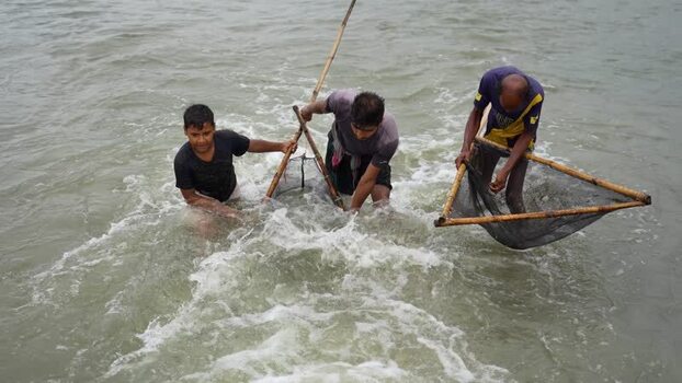 View of fishermen using traditional nets in a river Bangladesh.