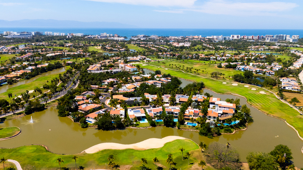 Aerial view of serene waters reflecting the sky amidst lush green golf courses and luxury homes Riviera Nayarit Mexico