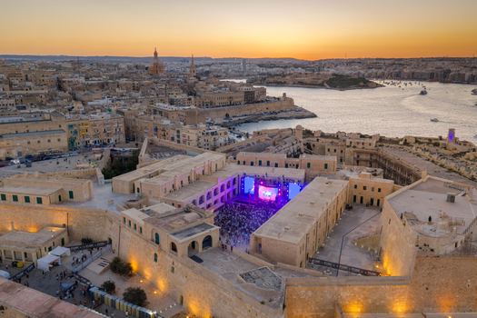 Aerial view of a concert taking place in the courtyard of Fort St. Elmo with blue stage lights surrounded by historic limestone walls at sunset in Valletta Port Region Malta. Aerial view of a concert taking place in the courtyard of Fort St. Elmo with blue stage lights surrounded by historic limestone walls at sunset in Valletta Port Region Malta.