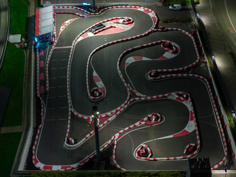Aerial view of an illuminated go kart track at night with red and white safety barriers and asphalt curves in Warsaw Masovian Voivodeship Poland.