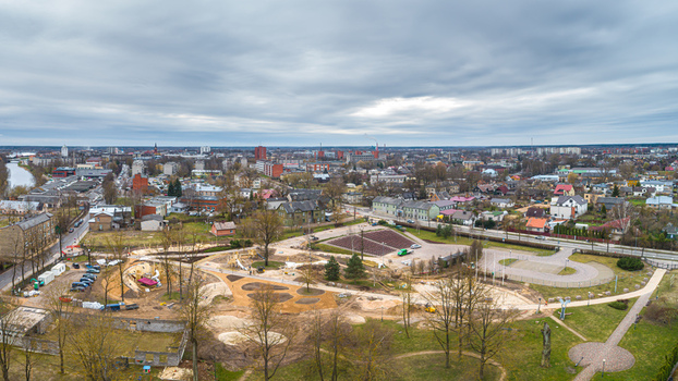 Aerial view of a town featuring a park area under development residential buildings roads and a river under a cloudy sky in Latvia. Aerial view of a town featuring a park area under development residential buildings roads and a river under a cloudy sky in Latvia.