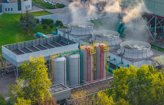 Aerial view of industrial cooling towers storage vessels pipelines and steam at an energy production facility in Brescia Lombardy Italy.