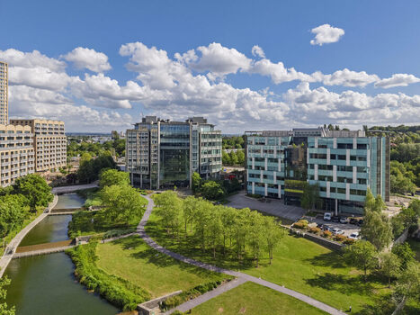 Aerial view of modern office buildings situated along a canal with lush green parkland and pathways in London England United Kingdom. Aerial view of modern office buildings situated along a canal with lush green parkland and pathways in London England United Kingdom.