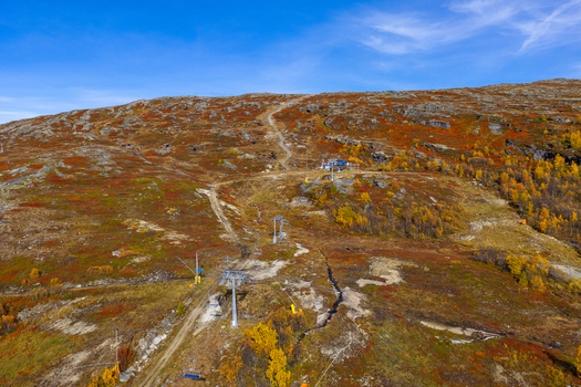Aerial view of a ski lift on a mountain slope with autumn foliage rocky terrain and a clear blue sky in Bjorli Innlandet Norway. Aerial view of a ski lift on a mountain slope with autumn foliage rocky terrain and a clear blue sky in Bjorli Innlandet Norway.
