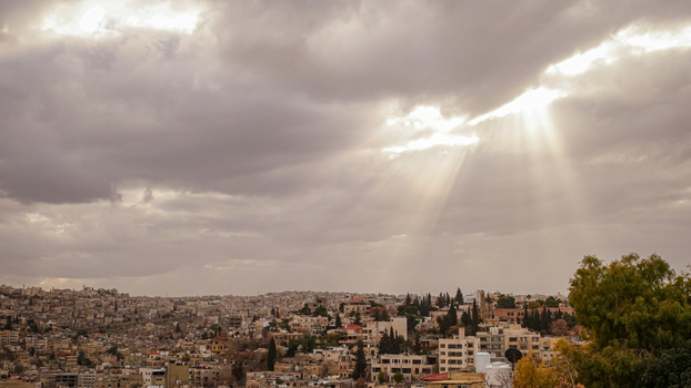View of the historic city of Jerash with dramatic sunbeams breaking through heavy clouds over the urban landscape in Jerash Jerash Governorate Jordan. View of the historic city of Jerash with dramatic sunbeams breaking through heavy clouds over the urban landscape in Jerash Jerash Governorate Jordan.