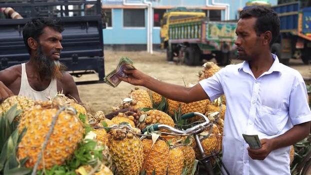 View of men trading money for pineapples at a market Bangladesh. View of men trading money for pineapples at a market Bangladesh.