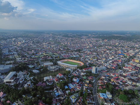 Aerial view of Segiri Stadium surrounded by the dense urban landscape with residential rooftops roads and lush greenery Samarinda East Kalimantan Indonesia.