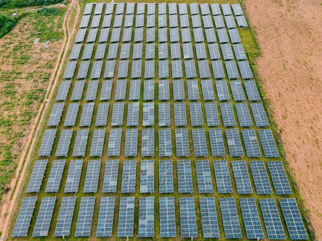 Aerial view of a large solar farm with rows of photovoltaic panels installed on open land in Ogun State Nigeria.