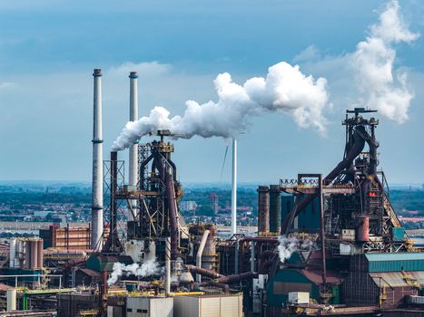 Aerial view of Tata Steel industrial plant with tall chimneys emitting smoke complex metal structures and surrounding urban landscape in Velsen Noord Noord Holland Netherlands. Aerial view of Tata Steel industrial plant with tall chimneys emitting smoke complex metal structures and surrounding urban landscape in Velsen Noord Noord Holland Netherlands.