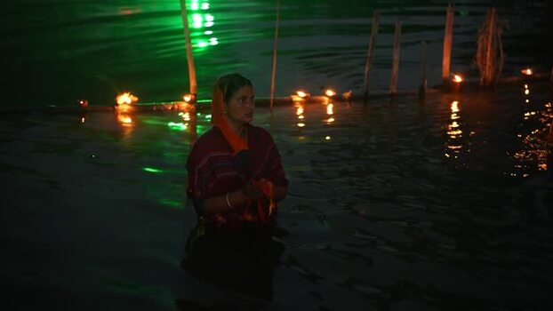 View of a woman praying in water with oil lamps at night Bangladesh. View of a woman praying in water with oil lamps at night Bangladesh.