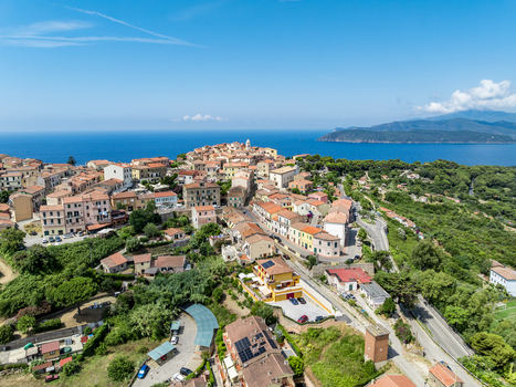Aerial view of the historic town of Capoliveri with its dense cluster of terracotta roofed buildings narrow streets and lush landscape overlooking the sea in Capoliveri Tuscany Italy.