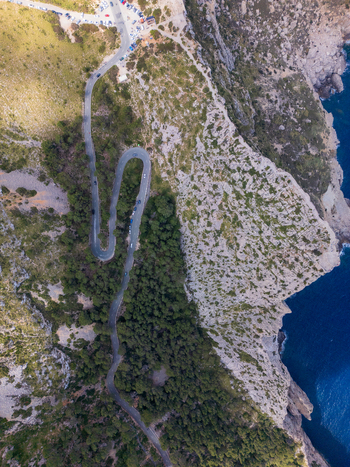 Aerial view of the winding road at Cap de Formentor with steep rocky cliffs and lush green vegetation overlooking the blue sea in Balearic Islands Balearic Islands Spain.