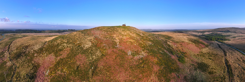 Aerial view of Chapelle Saint Michel de Brasparts on top of a hill surrounded by vast moorland and heath under a clear blue sky Saint Rivoal Bretagne France. Aerial view of Chapelle Saint Michel de Brasparts on top of a hill surrounded by vast moorland and heath under a clear blue sky Saint Rivoal Bretagne France.