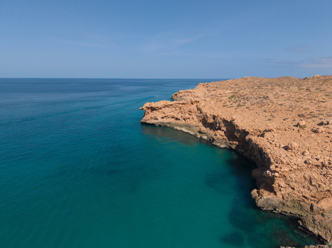 Aerial view of turquoise waters meet the rugged sun baked cliffs of the Socotra coastline a vibrant contrast under the clear sky Siqirah Socotra Yemen. Aerial view of turquoise waters meet the rugged sun baked cliffs of the Socotra coastline a vibrant contrast under the clear sky Siqirah Socotra Yemen.