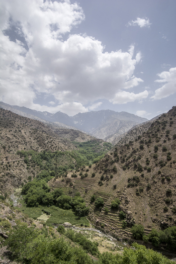 View of the mountain village of Tizi Oussem with terraced fields and rocky slopes under a cloudy sky in the High Atlas Mountains Tizi Oussem Marrakech Safi Morocco. View of the mountain village of Tizi Oussem with terraced fields and rocky slopes under a cloudy sky in the High Atlas Mountains Tizi Oussem Marrakech Safi Morocco.