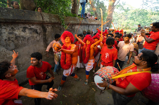 Munshiganj Bangladesh 13 April 2025 View of an energetic procession of devotees in vivid red and orange faces painted amidst rhythmic drumming. Munshiganj Bangladesh 13 April 2025 View of an energetic procession of devotees in vivid red and orange faces painted amidst rhythmic drumming.