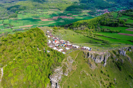Aerial view of the Walberla hill during a festival with white tents crowds of people and a small chapel surrounded by rocky cliffs and green forests in Kirchehrenbach Bavaria Germany. Aerial view of the Walberla hill during a festival with white tents crowds of people and a small chapel surrounded by rocky cliffs and green forests in Kirchehrenbach Bavaria Germany.