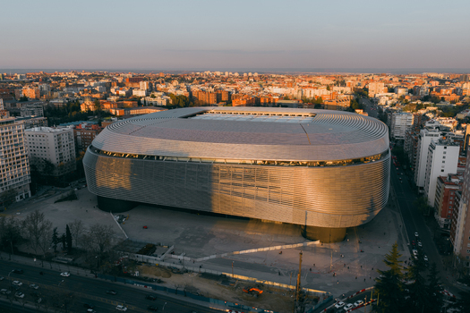 Aerial view of the modern metallic facade of Santiago Bernabeu stadium during golden hour in the urban landscape of Madrid Community of Madrid Spain. Aerial view of the modern metallic facade of Santiago Bernabeu stadium during golden hour in the urban landscape of Madrid Community of Madrid Spain.