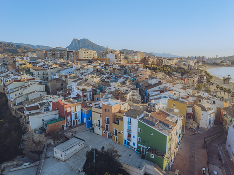 Aerial view of colorful houses and the sandy beach with mountains in the background under a clear blue sky in La Vila Joiosa Valencian Community Spain. Aerial view of colorful houses and the sandy beach with mountains in the background under a clear blue sky in La Vila Joiosa Valencian Community Spain.