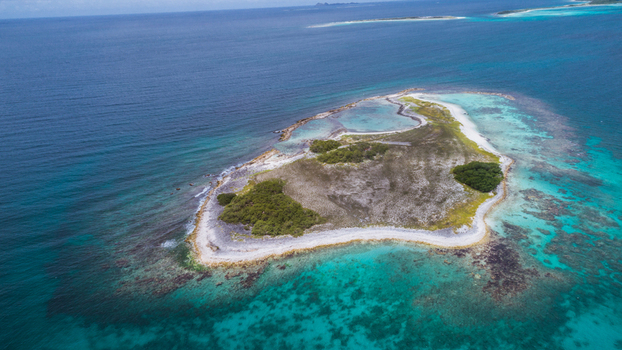 Aerial view of Los Roques archipelago featuring a small island surrounded by turquoise Caribbean waters coral reefs and white sandy beaches in Los Roques Dependencias Federales Venezuela. Aerial view of Los Roques archipelago featuring a small island surrounded by turquoise Caribbean waters coral reefs and white sandy beaches in Los Roques Dependencias Federales Venezuela.