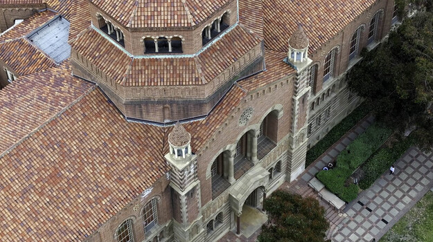 Aerial view of Royce Hall at UCLA Campus featuring Romanesque Revival architecture red tiled roof and arched windows surrounded by walkways and greenery in Westwood California United States.