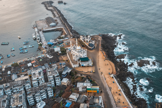 Aerial view of Vizhinjam Mosque situated on the rocky coastline surrounded by fishing boats in the harbor urban buildings and the Arabian Sea in Kovalam Keralam India. Aerial view of Vizhinjam Mosque situated on the rocky coastline surrounded by fishing boats in the harbor urban buildings and the Arabian Sea in Kovalam Keralam India.
