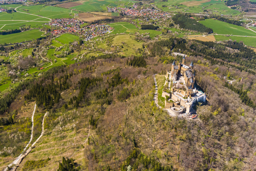 Burg Hohenzollern Germany 27 September 2026 Aerial view of Hohenzollern Castle perched on a mountain peak surrounded by dense forests and rolling green fields in the Swabian Alps.