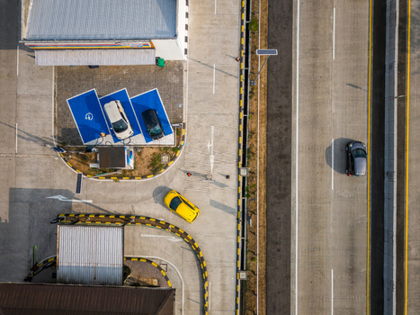 Aerial view of a modern electric vehicle charging station with parked cars and a yellow vehicle maneuvering near a highway in Salatiga Central Java Indonesia. Aerial view of a modern electric vehicle charging station with parked cars and a yellow vehicle maneuvering near a highway in Salatiga Central Java Indonesia.